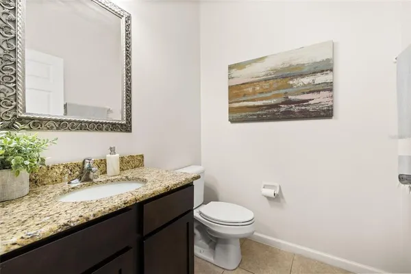 a bathroom with a granite countertop sink mirror vanity and toilet