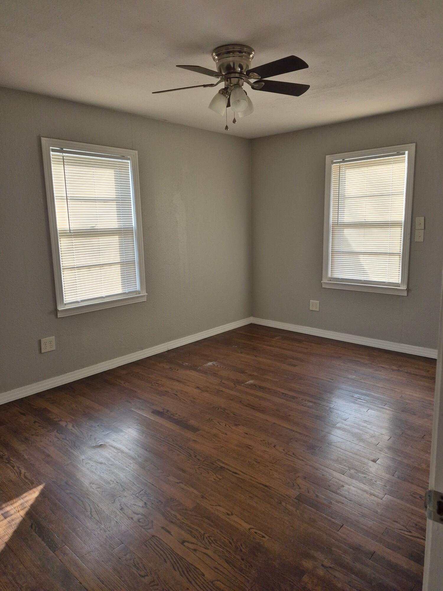 3517 30th Street Lubbock, TX 79410 - Photo 15 of 18 an empty room with wooden floor chandelier fan and windows