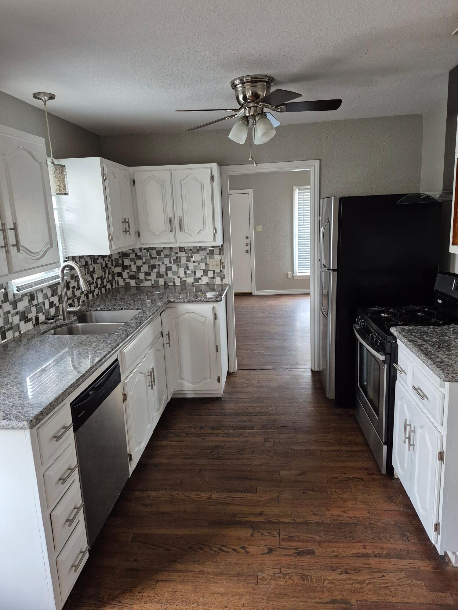 3517 30th Street Lubbock, TX 79410 - Photo 4 of 18 a kitchen with stainless steel appliances wooden floors wooden cabinets a sink and a stove