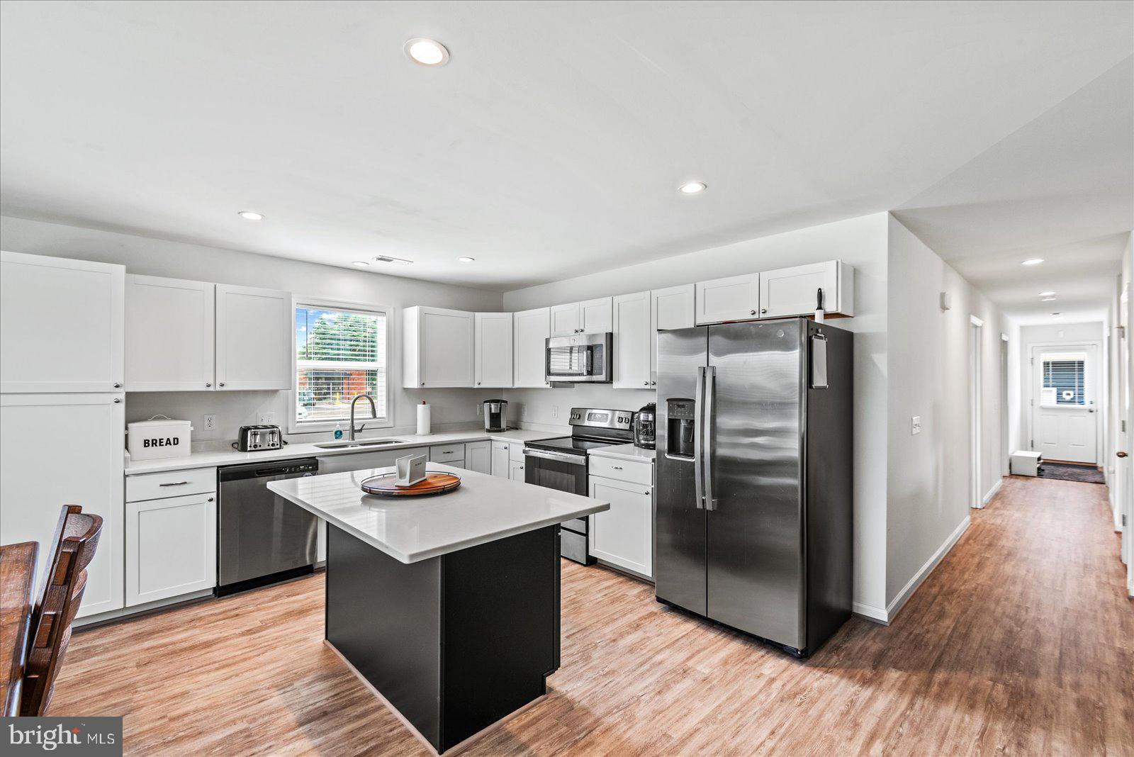 121 1st Street Colonial Beach, VA 22443 - Photo 10 of 46 a kitchen with stainless steel appliances granite countertop a stove top oven a refrigerator a sink and dishwasher with wooden floor