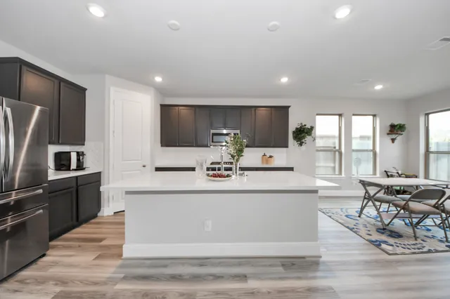 a large white kitchen with kitchen island granite countertop a large counter top stainless steel appliances and cabinets