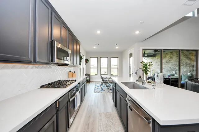 a kitchen with stainless steel appliances a sink stove and cabinets