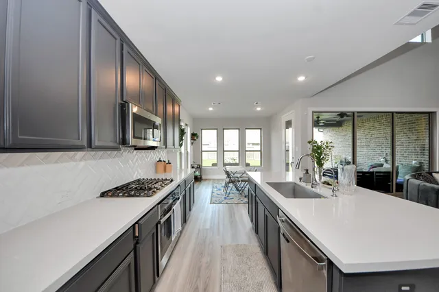 a kitchen with stainless steel appliances a sink a stove and a wooden cabinets