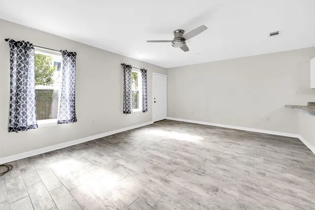 a view of an empty room with wooden floor and a window