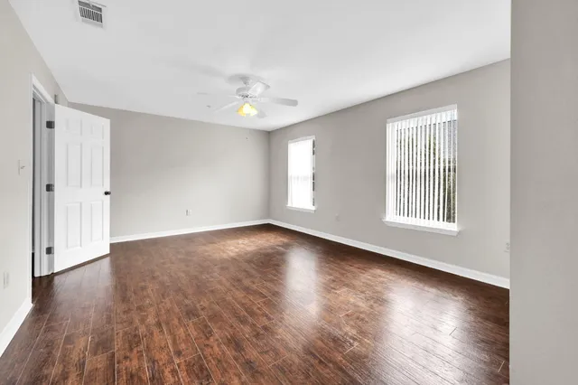 an empty room with wooden floor and windows