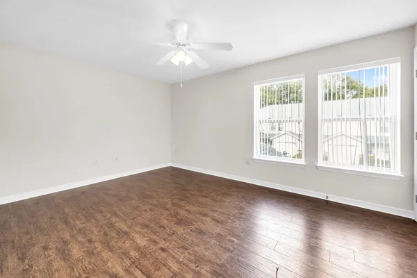 an empty room with wooden floor and windows