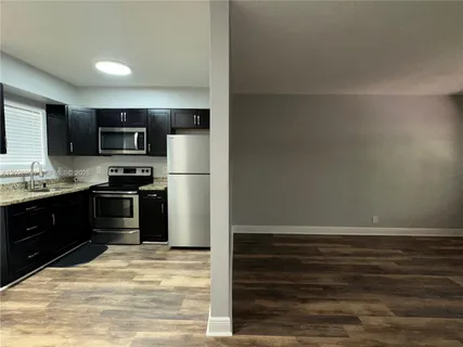 a kitchen with granite countertop a refrigerator and a stove top oven