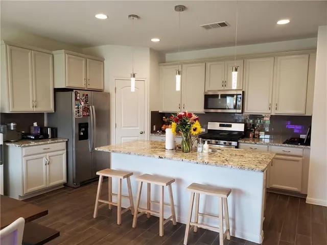 a kitchen with stainless steel appliances granite countertop a stove a sink a refrigerator a microwave and white cabinets