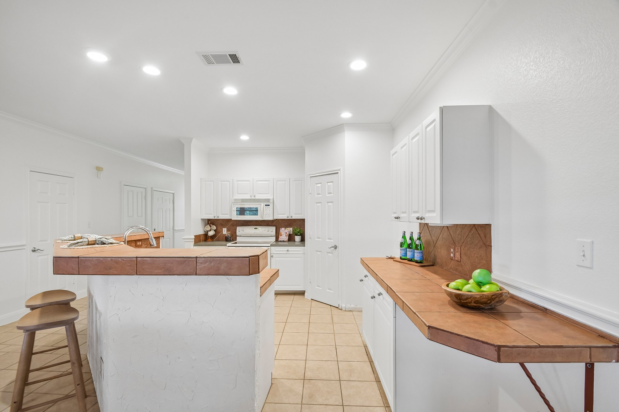 20609 Bridle Path Road Lago Vista, TX 78645 - Photo 13 of 30 A well-lit kitchen with classic white cabinetry and practical tile flooring.