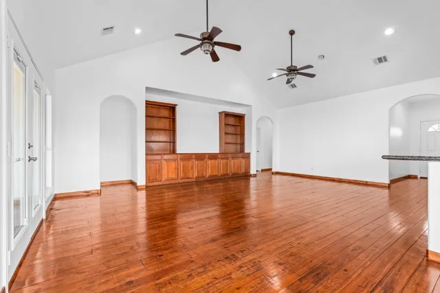 a view of empty room with wooden floor and fan