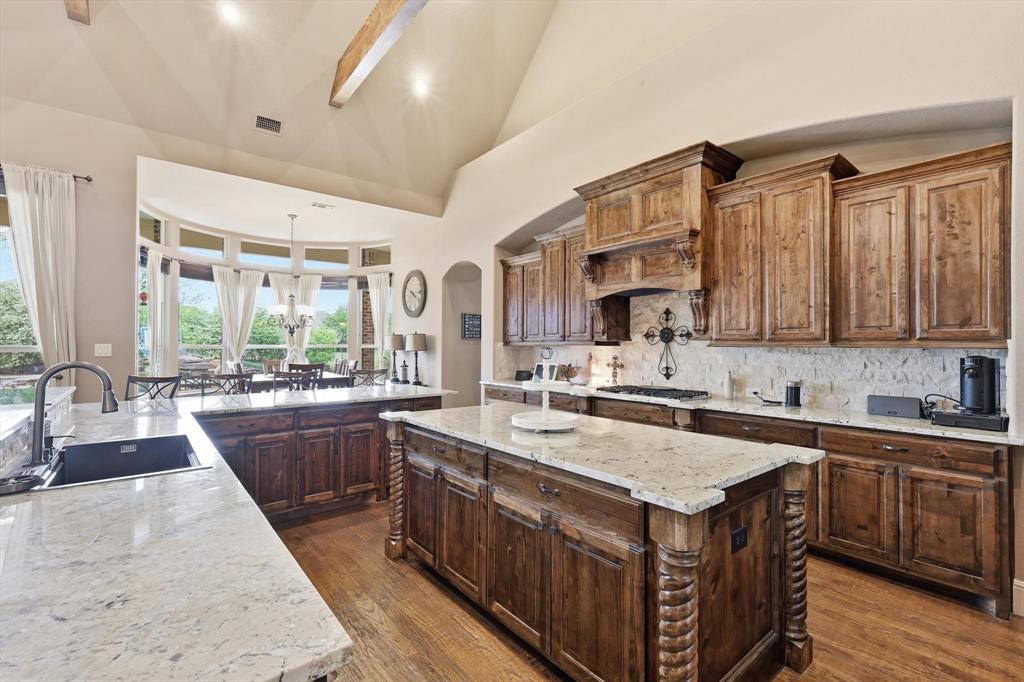 406 Spurgin Road Lucas, TX 75002 - Photo 9 of 39 Kitchen with a center island, light stone countertops, decorative backsplash, lofted ceiling, and dark wood-style flooring