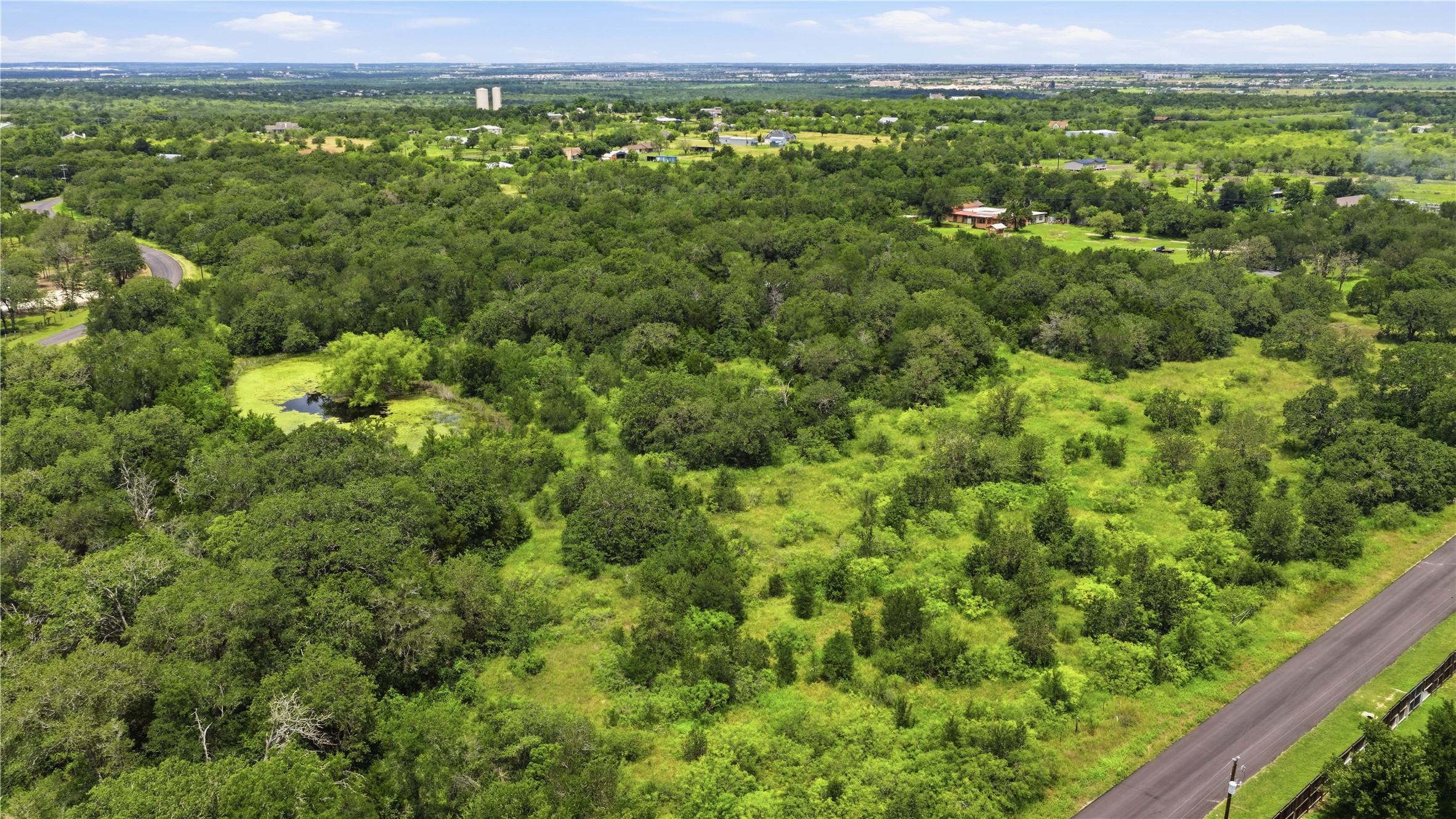 10312 Parsons Road Manor, TX 78653 - Photo 20 of 26 A verdant landscape provides a serene setting with mature trees and a tranquil pond, perfect for a private estate.