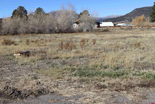 a view of a dry yard with a barn in the background