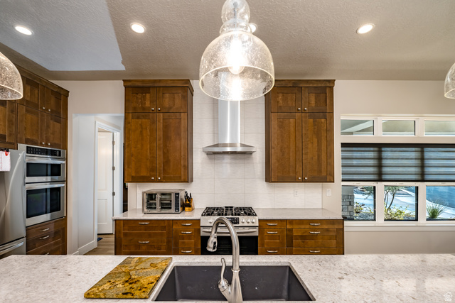 1283 North Gallen Road Santa Clara, UT 84765 - Photo 19 of 103 Kitchen with pendant lighting, stainless steel appliances, light stone counters, a textured ceiling, and wood finish cabinetry