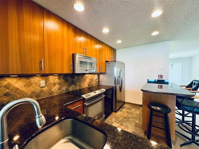 a kitchen with stainless steel appliances granite countertop sink stove refrigerator and microwave