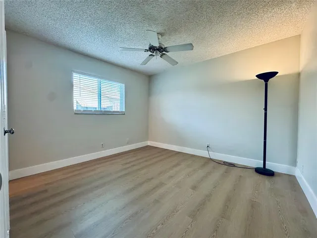 an empty room with wooden floor chandelier fan and windows