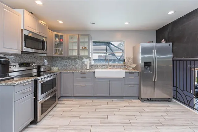 a kitchen with stainless steel appliances granite countertop a refrigerator and a stove top oven