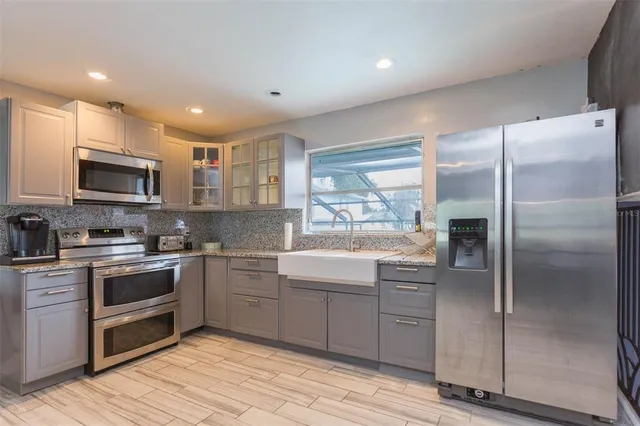 a kitchen with kitchen island granite countertop a sink stainless steel appliances and counter space