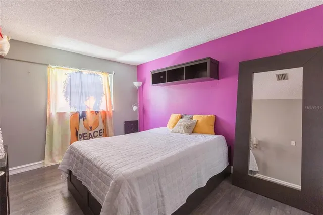 a bedroom with a bed and a dresser with wooden floor