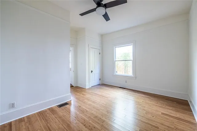 a view of empty room with wooden floor and fan