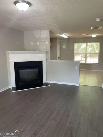 a view of an empty room with wooden floor and a fireplace