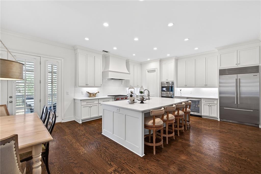 4774 Wieuca Road Northeast Atlanta, GA 30342 - Photo 12 of 52 a kitchen with stainless steel appliances a table chairs sink refrigerator and cabinets