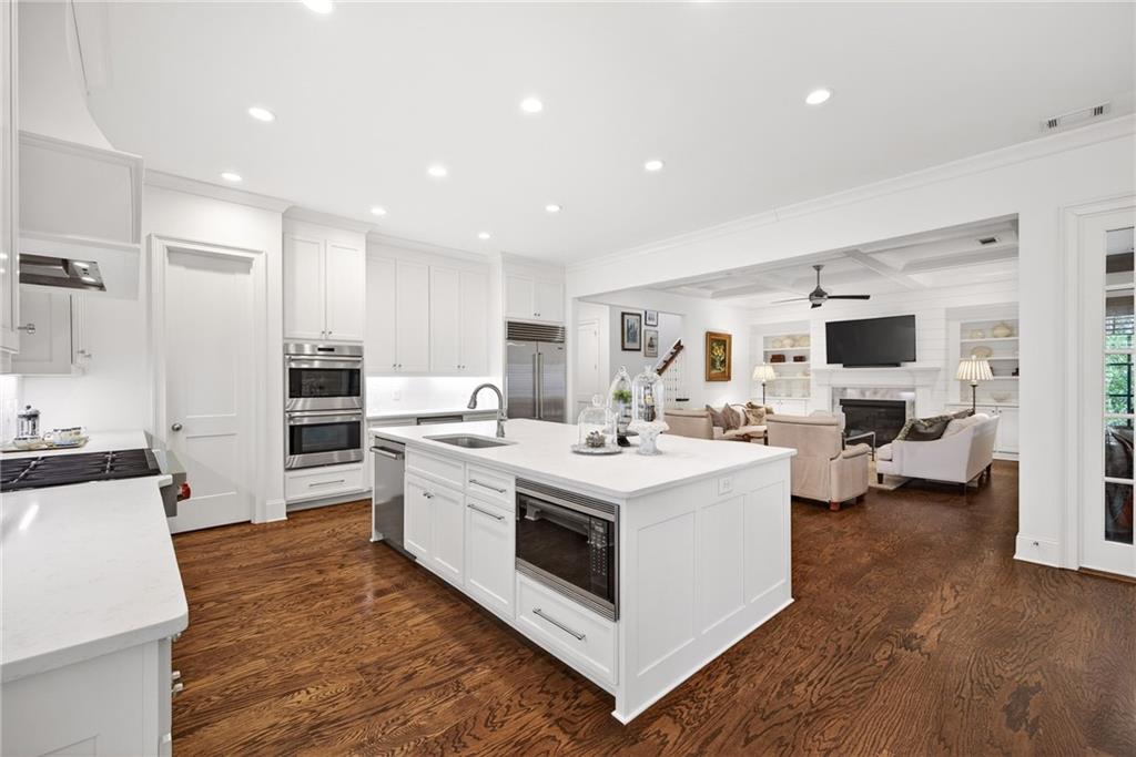 4774 Wieuca Road Northeast Atlanta, GA 30342 - Photo 15 of 52 a large white kitchen with a stove top oven a sink dishwasher and a refrigerator with wooden floor