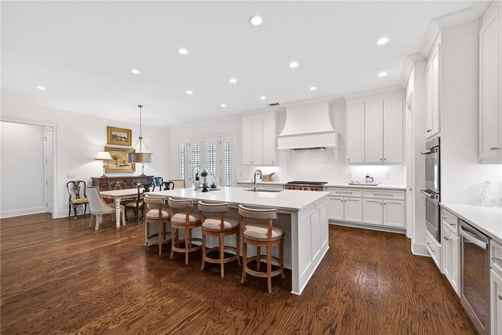 4774 Wieuca Road Northeast Atlanta, GA 30342 - Photo 4 of 52 a large kitchen with kitchen island a dining table chairs and white cabinets