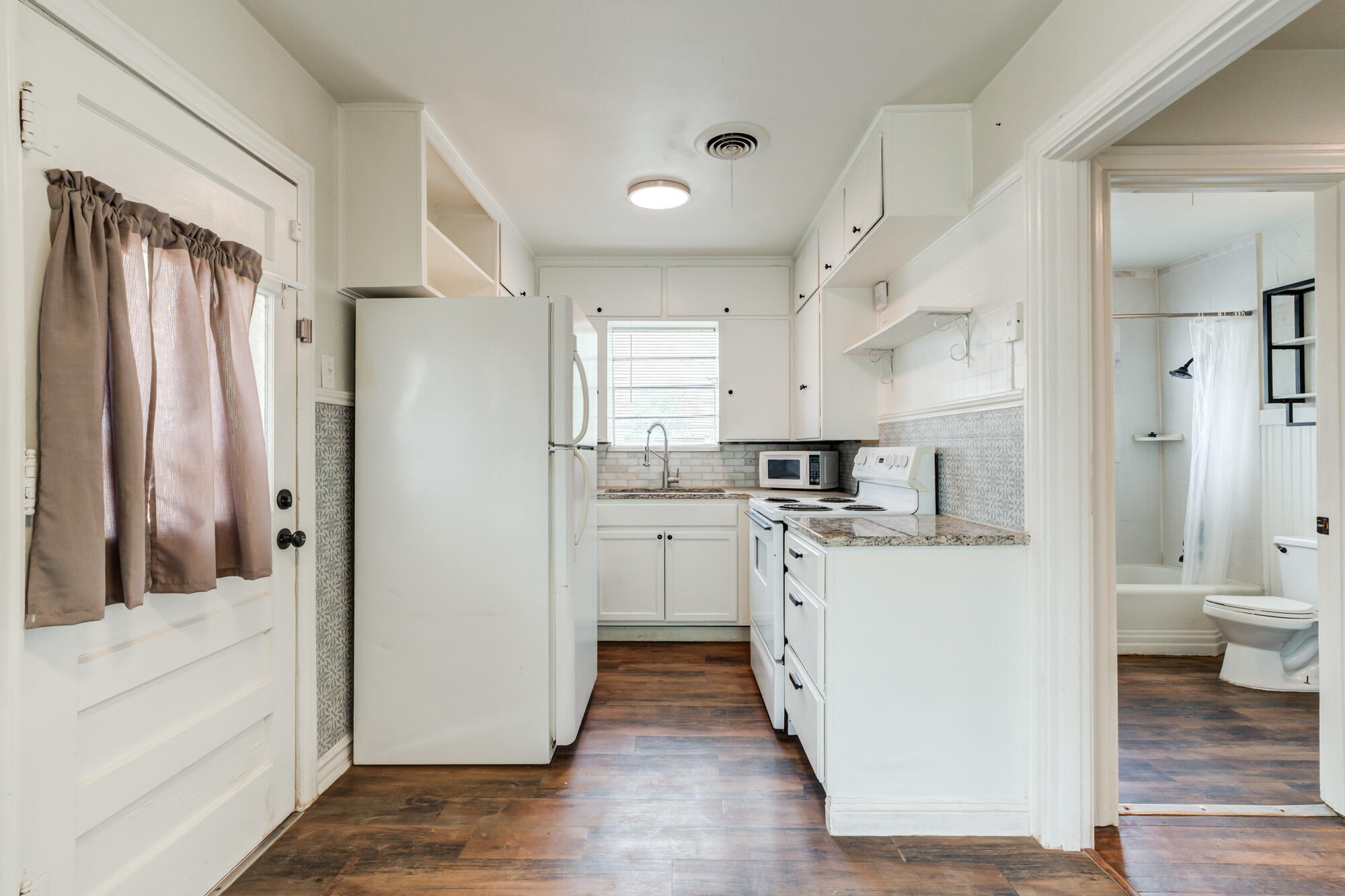 2308 30th Street Lubbock, TX 79411 - Photo 11 of 21 a kitchen with white cabinets and white appliances