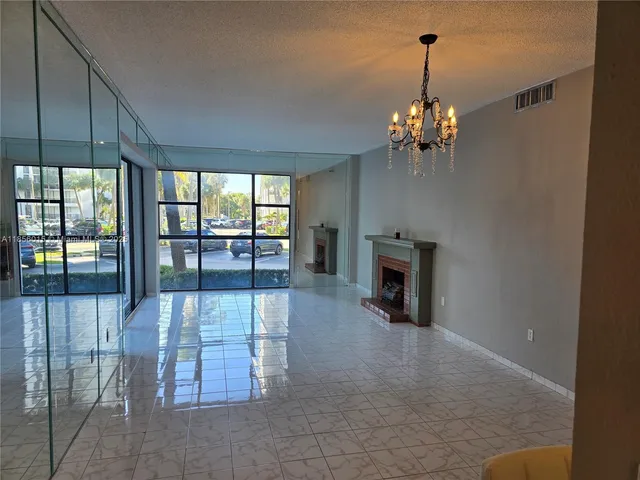 a view of a livingroom with a fireplace a chandelier and windows