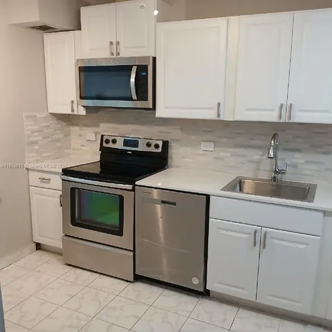 a kitchen with white cabinets and stainless steel appliances