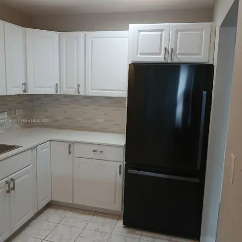 a kitchen with a refrigerator and white cabinets
