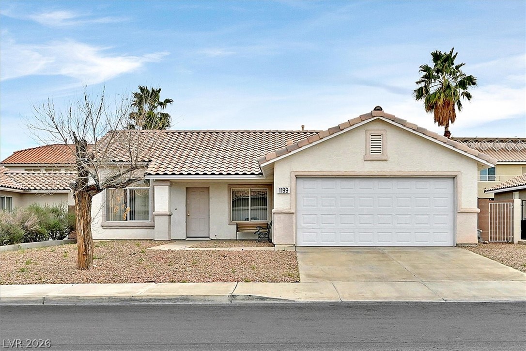 View of front of home with a tile roof, driveway, stucco siding, and an attached garage