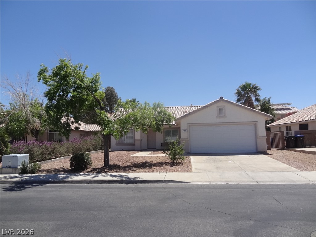 View of front facade featuring an attached garage, concrete driveway, stucco siding, and a tile roof