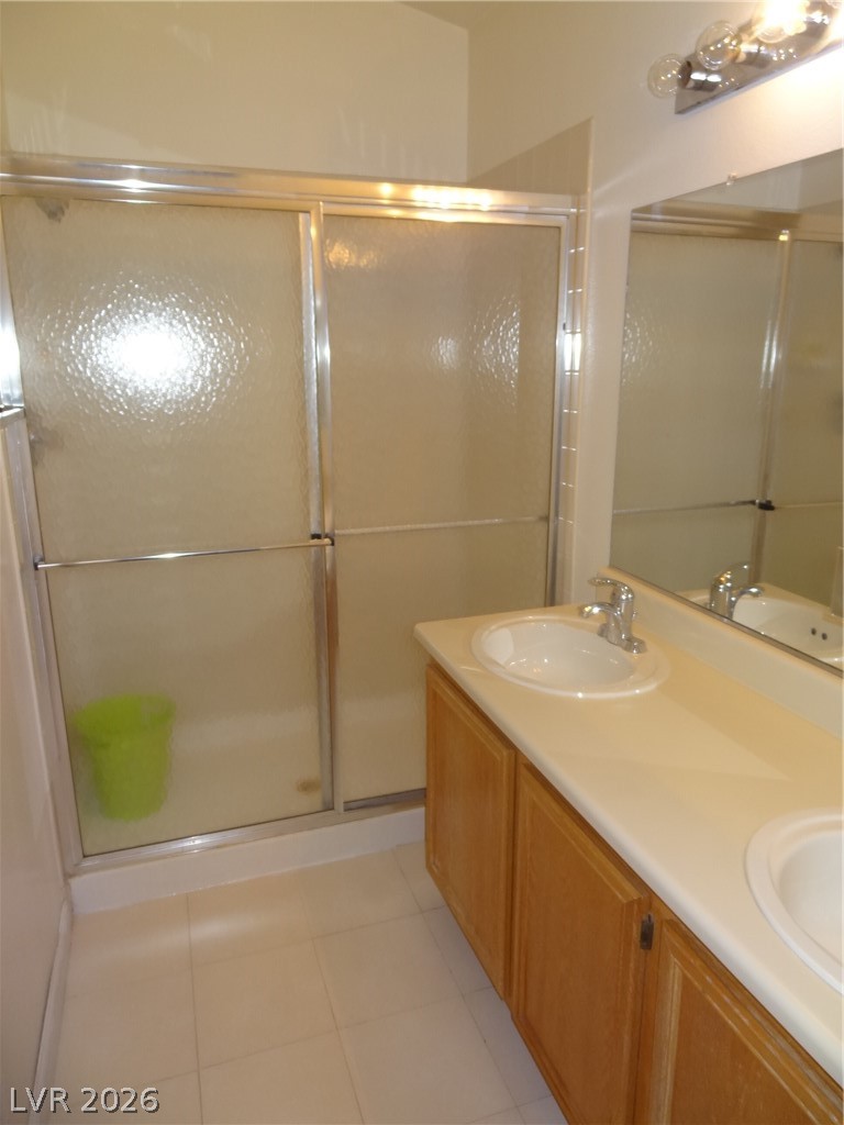 1199 Sunfire Street Henderson, NV 89014 - Photo 7 of 11 Bathroom with light tile patterned floors, double vanity, and a shower stall