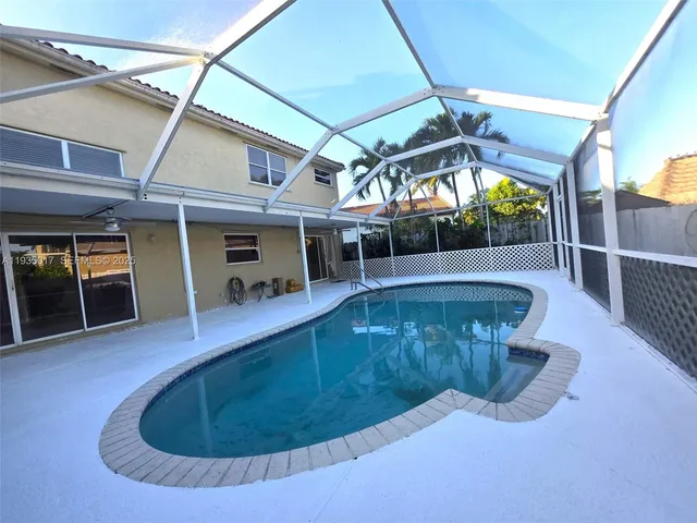 a view of a swimming pool with a patio and a yard
