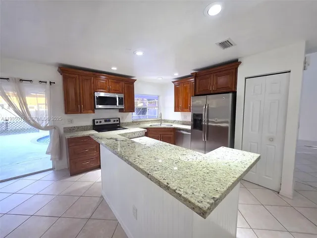 a kitchen with stainless steel appliances granite countertop a sink dishwasher stove top oven and refrigerator