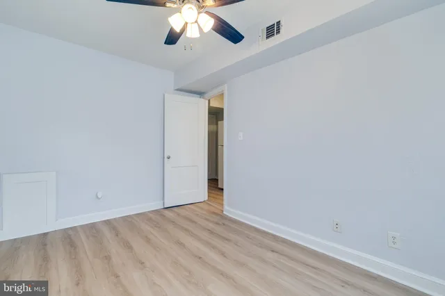 an empty room with a chandelier fan and wooden floor