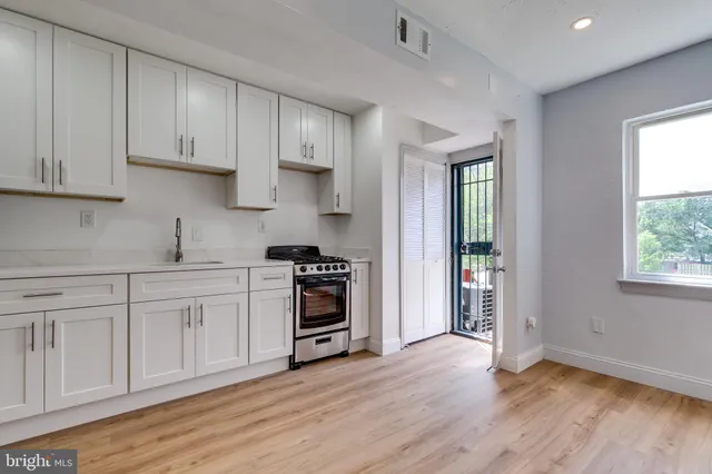 a kitchen with stainless steel appliances granite countertop a stove a sink and white cabinets