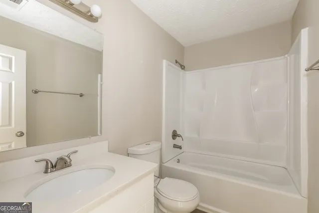 a bathroom with a bathtub shower sink vanity and toilet