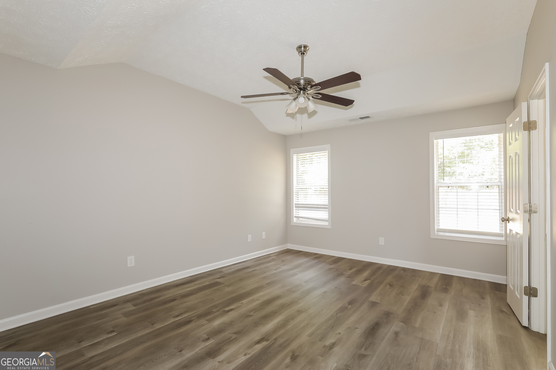 125 Waters Edge Drive Locust Grove, GA 30248 - Photo 7 of 16 a view of empty room with wooden floor and fan