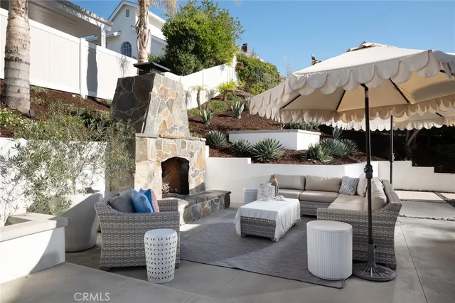 a view of a patio with couches table and chairs under an umbrella with a fire pit