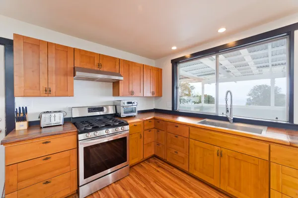 a kitchen with granite countertop stainless steel appliances a stove sink and cabinets