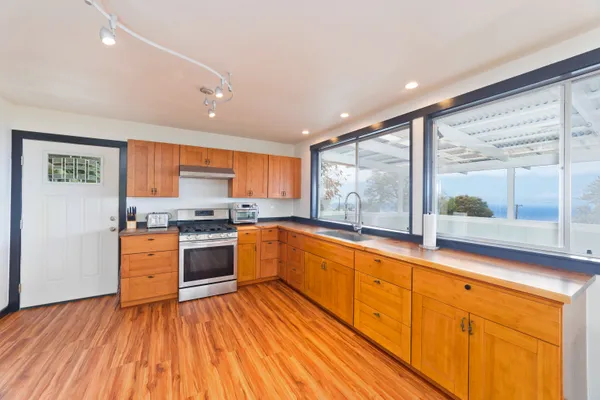 a large kitchen with stainless steel appliances granite countertop white cabinets and wooden floors