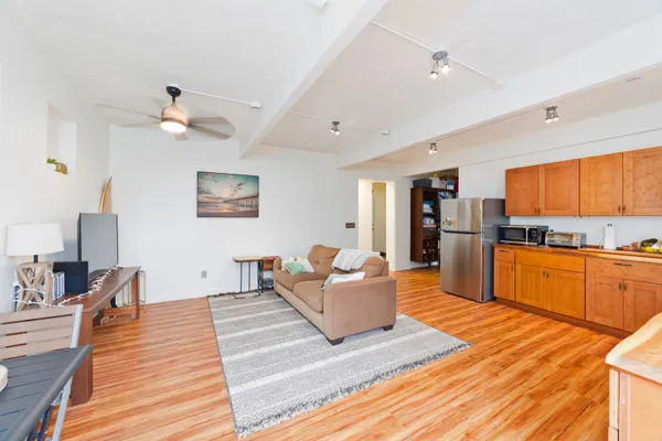 a living room with stainless steel appliances kitchen island granite countertop furniture and a wooden floor