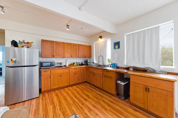 a kitchen with stainless steel appliances granite countertop a refrigerator a sink dishwasher a stove with wooden cabinets and wooden floor