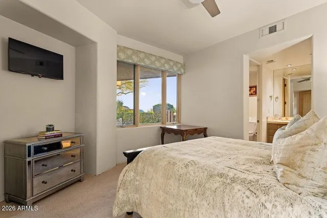 a bedroom with a bed and a flat tv screen on dresser