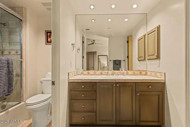 a bathroom with a granite countertop sink a toilet and a mirror