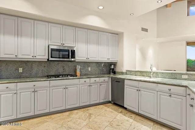 a kitchen with kitchen island granite countertop white cabinets white stainless steel appliances and a sink