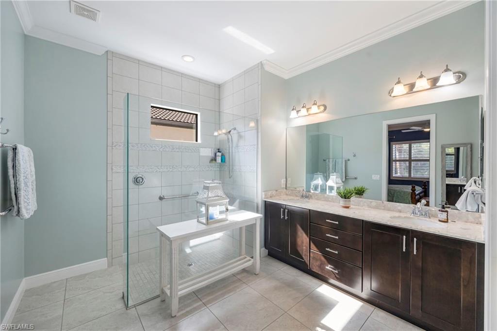 1287 Manado Drive Naples, FL 34113 - Photo 15 of 32 a spacious bathroom with a double vanity sink a mirror and a bathtub